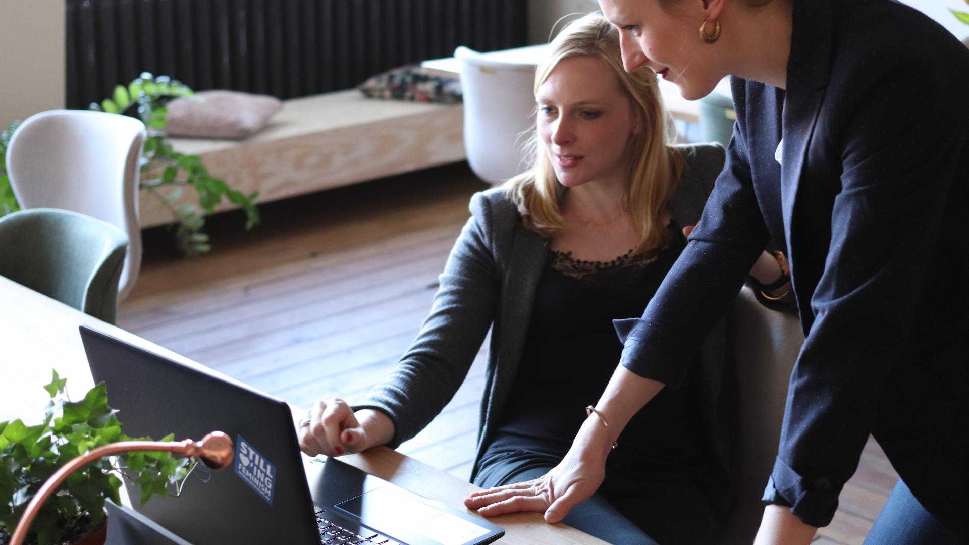 Une manager conseille sa salariée installée devant son ordinateur - Team building